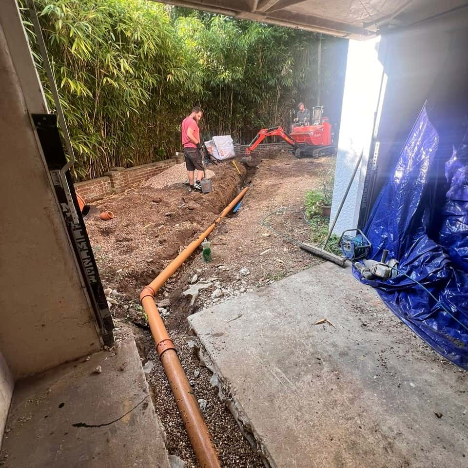 Installing new drainage pipes outside under a covered area.